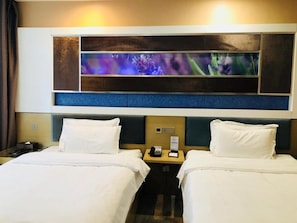 A hotel room with two beds, a large abstract painting above the beds, and a nightstand with a phone and a lamp. - Lavande Hotel (Lanzhou)