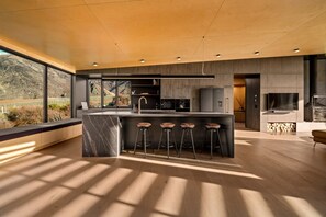 Een moderne keuken met een groot eiland, barstoelen en uitzicht op het buiten.