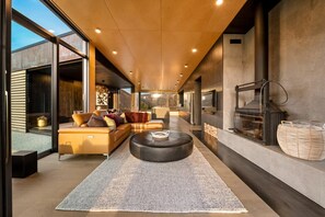 Een modern interieur met een bank, poef en een open haard.