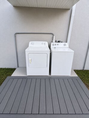 Two white front-loading washing machines on a grey platform with a grey roof overhead. - Private-Patio Studio near Miami Beach (Miami)