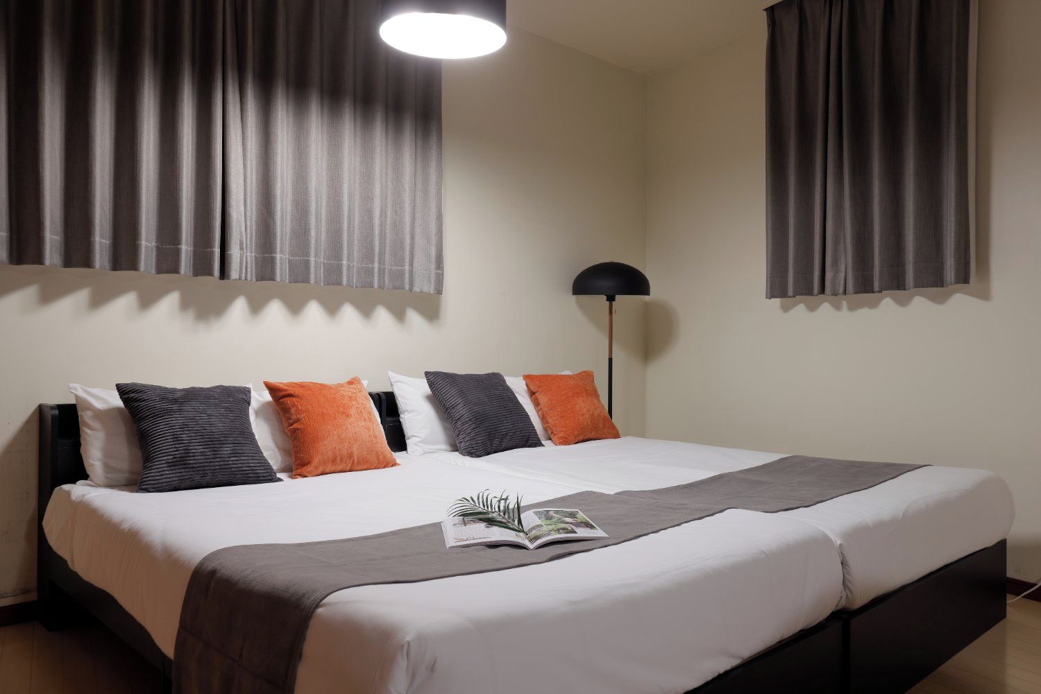 Una habitación de hotel con una cama grande, una lámpara de pie y cortinas.