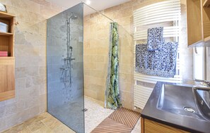 A modern bathroom with a glass shower enclosure, a wooden vanity, and a patterned tile backsplash. - Piscine, spa et littoral (SAINT-ANDRE-D'HERBERTO)