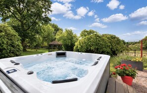 A hot tub in a garden with a gazebo and potted plants. - Piscine, spa et littoral (SAINT-ANDRE-D'HERBERTO)