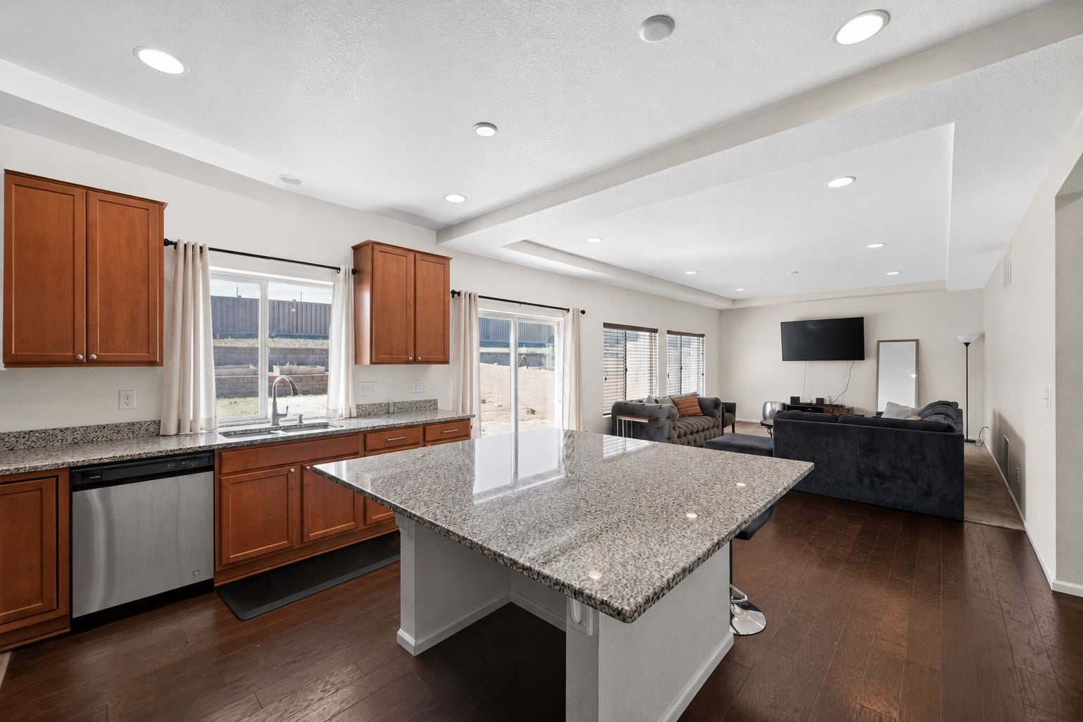 A modern kitchen with granite countertops, wooden cabinets, and a central island.