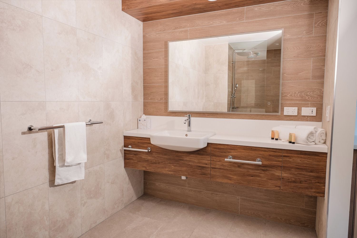 Une salle de bain moderne avec un double vasque, un meuble-lavabo en bois et un grand miroir.