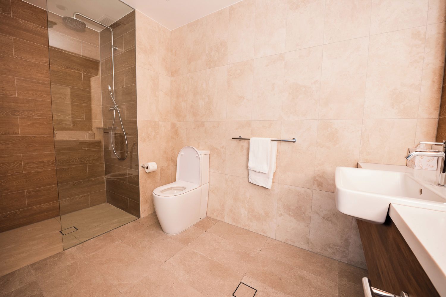 A modern bathroom with a glass-enclosed shower, a toilet, a sink, and a towel rack.