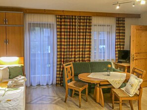 A room with a bed, a table with chairs, a sofa, and curtains.