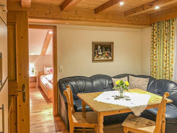 A cozy living room with a wooden table, leather sofa, and a painting on the wall.