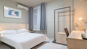 A hotel room with a bed, bedside table, and a desk with a lamp. - Jinjiang Inn (Weihai)