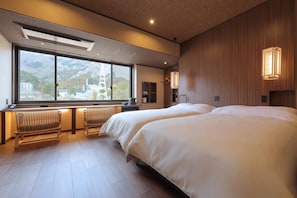 A hotel room with two beds, a large window with a view of mountains, a desk with a chair, and a radiator. - Tanigawa Hotel Nanaeyae (Nikko)