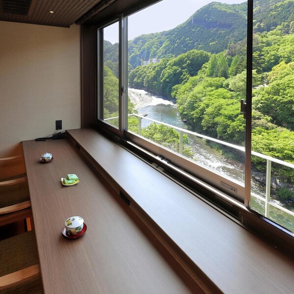 A room with a large window overlooking a river and forested hills. - Tanigawa Hotel Nanaeyae (Nikko)