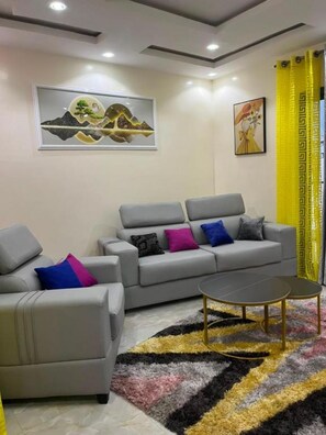A modern living room with a grey sofa, a coffee table, and a patterned rug. - Tranquil 1-bedroom apartment with AC in vibrant Dakar (Dakar)