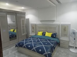 Quarto com cama, mesas de cabeceira, espelho e guarda-roupa.
