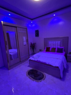Een slaapkamer met een bed, een kledingkast, een spiegel en een nachtkastje.