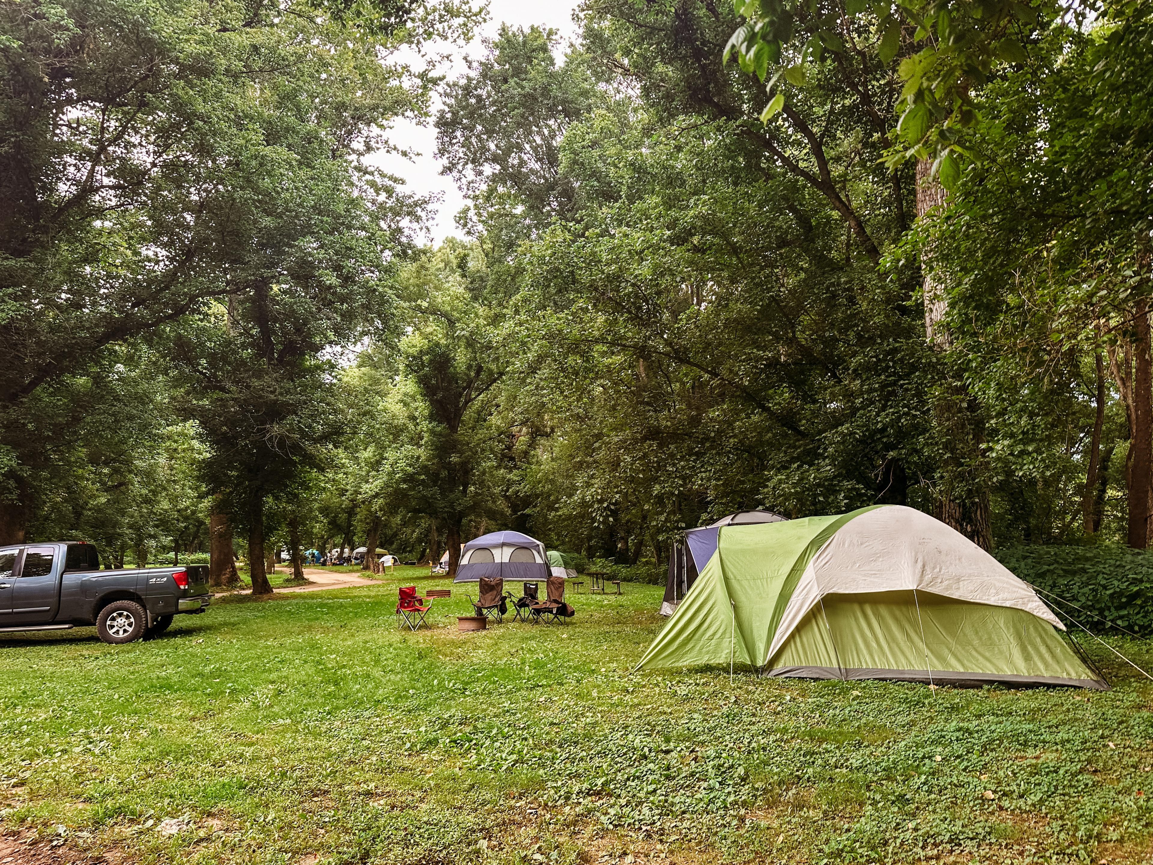 A campsite with tents, a truck, and a picnic table.