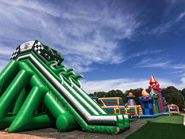 An inflatable play area with various structures including a slide and a castle-like playhouse.