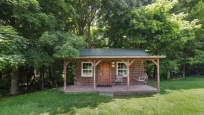 Een houten hut met een veranda, een deur en een raam.