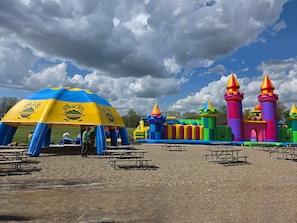 A family fun center with inflatable play structures and picnic tables.