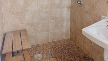 A bathroom with wooden paneling, a tiled floor, a sink, and a shower.
