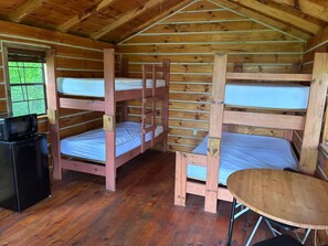 A cabin with bunk beds, a small table, and a microwave.