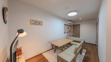 A room with a wooden dining table, bench seating, a lamp, and a wall-mounted clock.