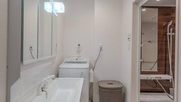A compact bathroom with a sink, mirror, and a shower area.