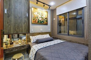 Quarto com cama, mesa de cabeceira, espelho, quadro e janela com cortinas.