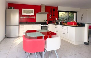 Una cocina moderna con una isla central, armarios blancos y una pared de acento roja.
