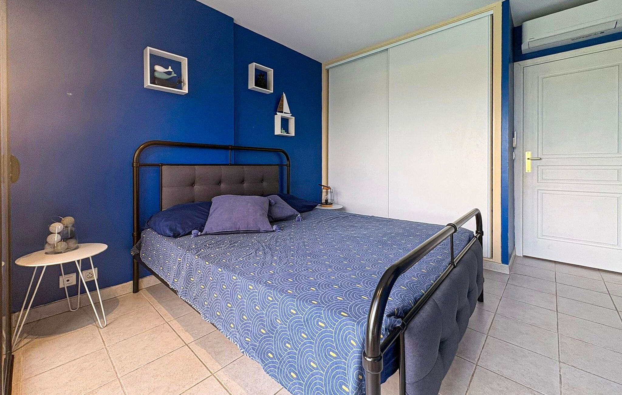 Une chambre à coucher avec un lit, une table de chevet, une lampe et une porte.