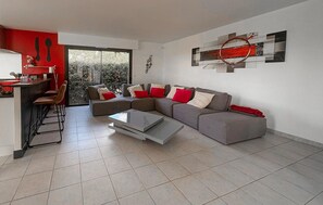 Ein modernes Wohnzimmer mit einer Eckcouch, einem Couchtisch und einer Küchenzeile mit Bar.