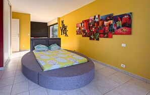 Un dormitorio con cama, cabecera, una pared decorada con obras de arte y una puerta.