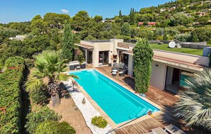 Una casa moderna con piscina, rodeada de exuberante vegetación y un paisaje montañoso.