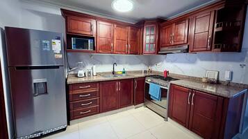 A kitchen with wooden cabinets, a refrigerator, a microwave, a stove, and a sink.