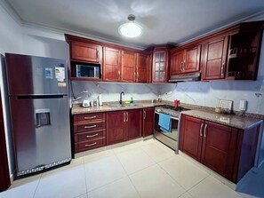 Cozinha com armários de madeira, geladeira, micro-ondas, fogão e pia.