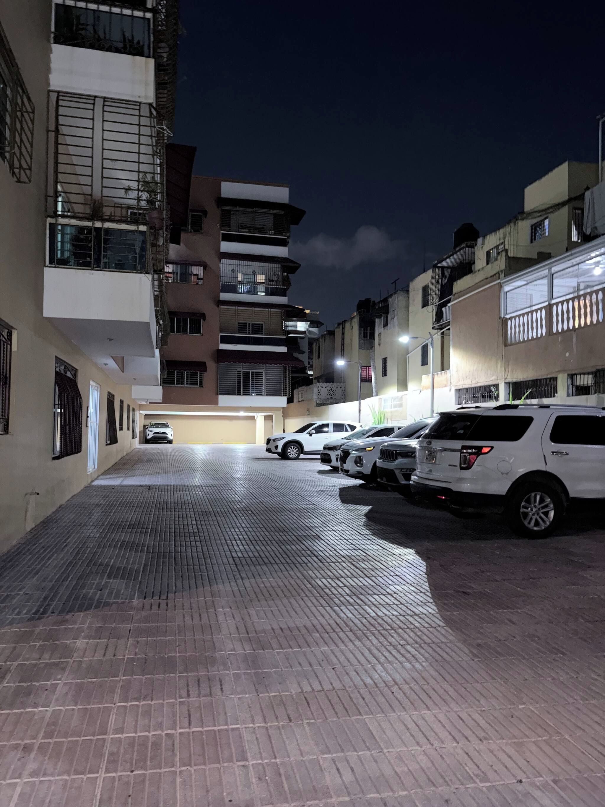 A parking area with multiple parked cars and a building with balconies.