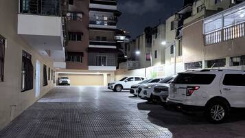 A parking area with multiple parked cars and a building with balconies.