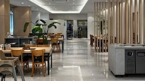 Ein modernes Interieur mit Essbereich, Tischen, Stühlen und Küchenzeile.