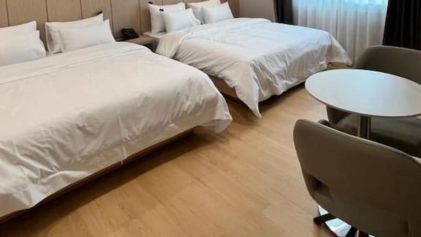 Ein Hotelzimmer mit zwei Betten, einem runden Tisch und einem Stuhl.