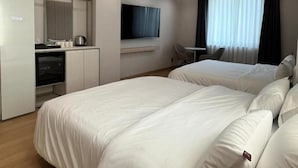 Ein Hotelzimmer mit Bett, Schreibtisch, Fernseher und einem Fenster mit Vorhängen.