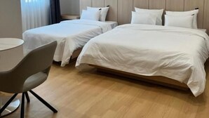 Ein Hotelzimmer mit zwei Betten, einem Schreibtisch und einem Fenster mit Vorhängen.