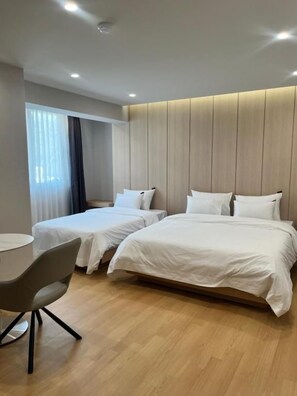 Quarto de hotel com duas camas, uma mesa de trabalho e uma janela com cortinas.