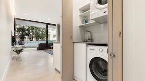 Une buanderie moderne équipée d’un lave-linge Bosch, d’un étendoir et d’une petite table sur laquelle se trouvent une tasse et une plante.