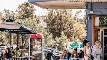 An outdoor seating area with tables and umbrellas, a coffee stand, and a sign for a coffee shop.