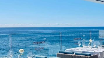 A dining area with tables set for a meal, overlooking the sea.