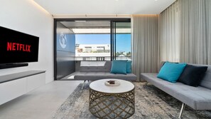 A modern living room with a flat-screen TV, a sofa, a coffee table, and a balcony with a view. - Sleek 1BR Apartment w Skylight near Coogee Beach (Coogee)