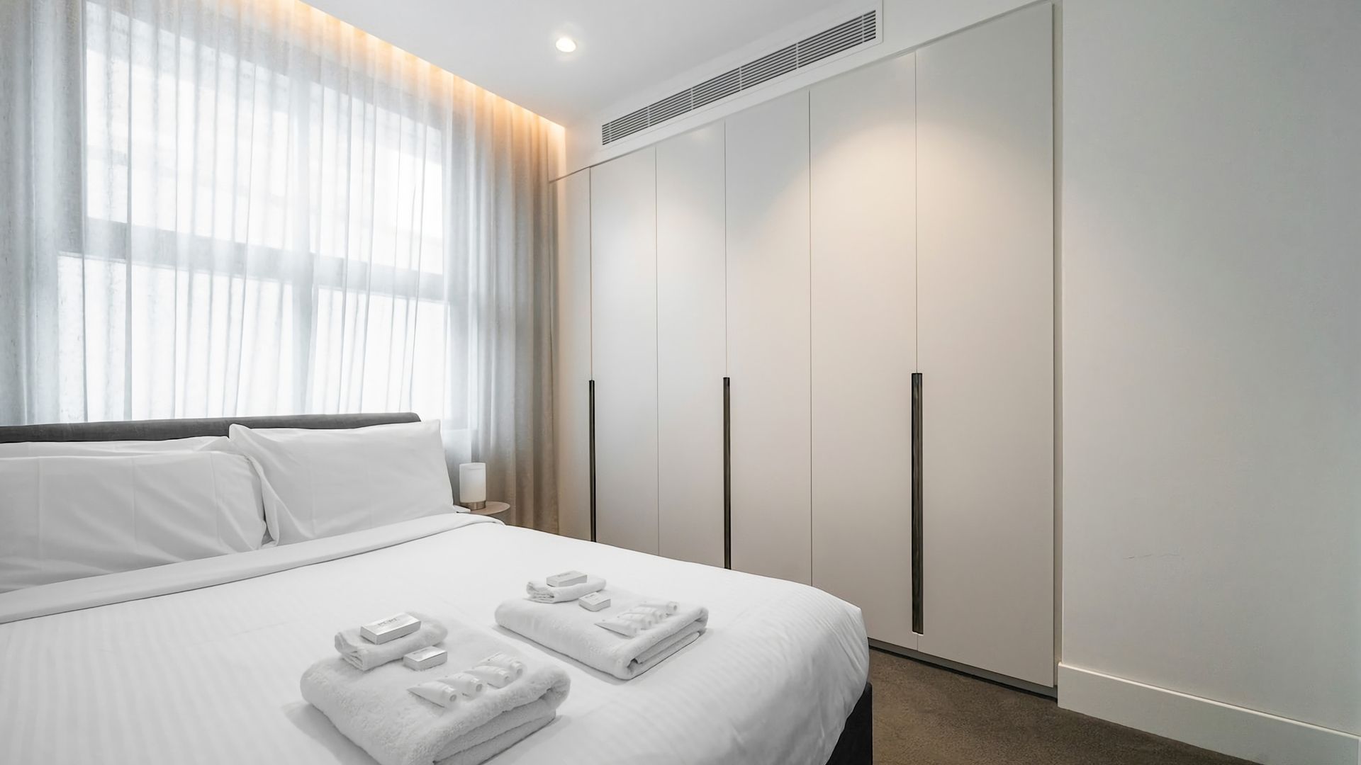 Une chambre d’hôtel avec un lit, une armoire et une table de chevet avec des serviettes.