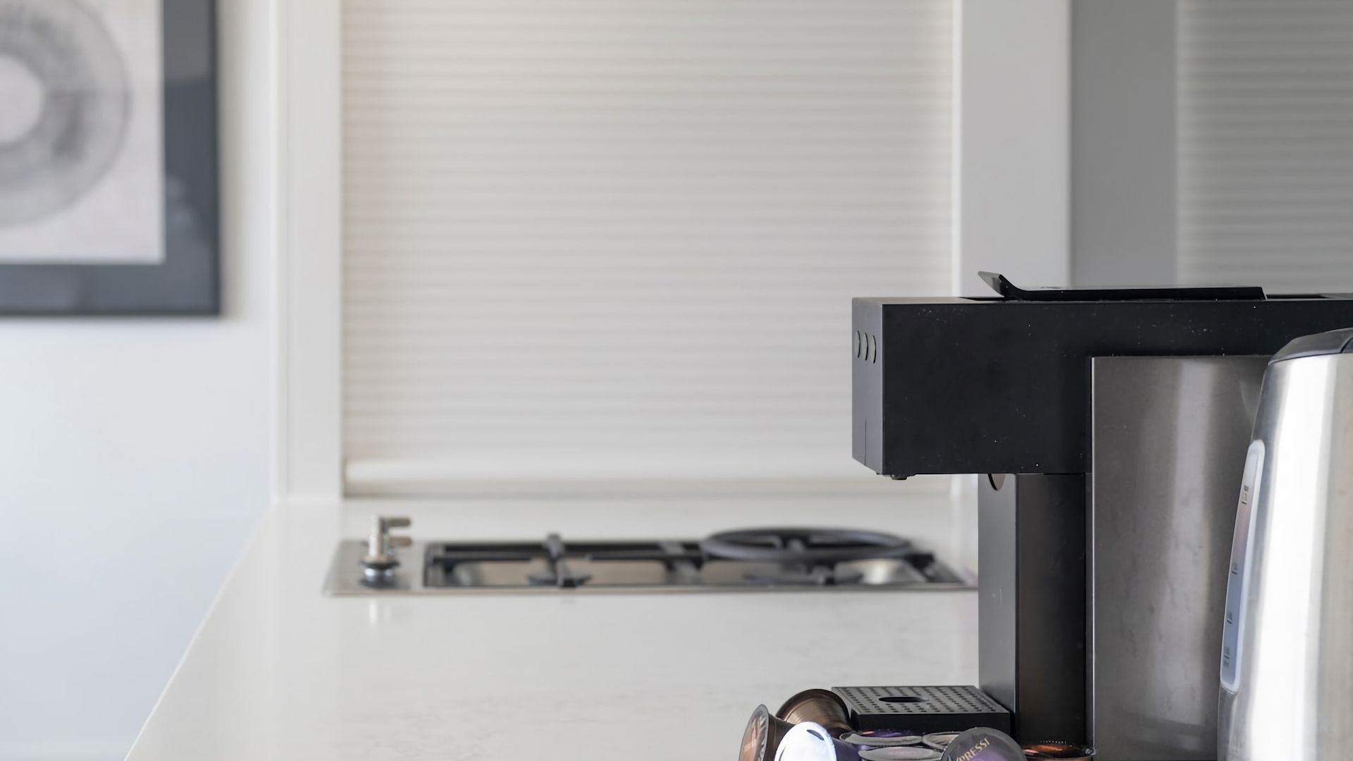A kitchen with a gas stove, a coffee machine, and a refrigerator.