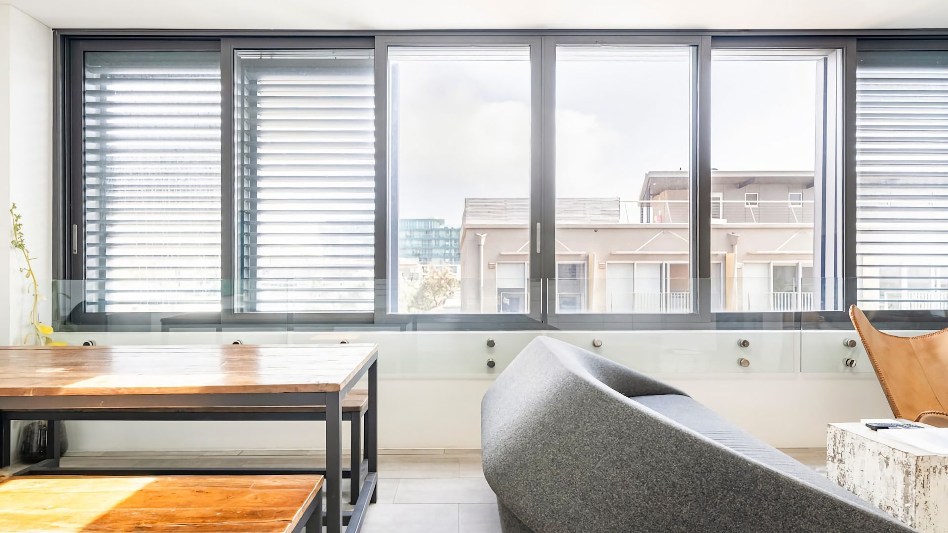 Una sala de estar moderna con un gran ventanal, una mesa de comedor y un sofá curvo.