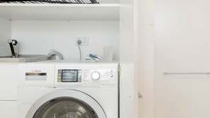 A white Bosch washing machine in a laundry room with a sink and a power outlet. - Top Floor Bondi Retreat Near Beach, Cafes & Dining (Bondi Beach)