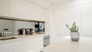 A modern kitchen with white cabinetry, a stainless steel sink, and a coffee maker. - Top Floor Bondi Retreat Near Beach, Cafes & Dining (Bondi Beach)
